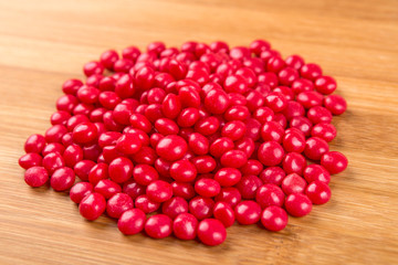 Red cinnamon candies isolated on a wood background
