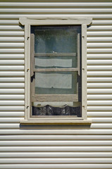 Wooden window frame on an old house with horizontal weatherboards on sunny day