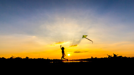 Kid flying a kite in sunset background