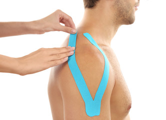Female hands applying physio tape onto patient shoulder, isolated on white