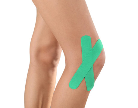 Female knees with physio tape on white background