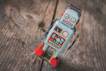 Spielzeug Blechroboter, Metapher für Social Bot / Chatbot auf Holzuntergrund