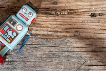 Spielzeug Blechroboter, Metapher für Social Bot / Chatbot auf Holzuntergrund, Draufsicht