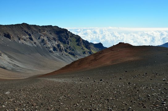 Looking down in the Haleakala Crater while clouds are being blown over the mountain ridge, Maui island, Hawaii