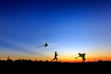 Fototapeta na wymiar Kid flying a kite in sunset background