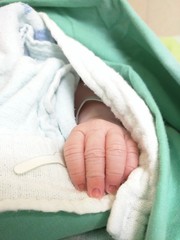 Newborn hand and fingers wrapped up in blankets