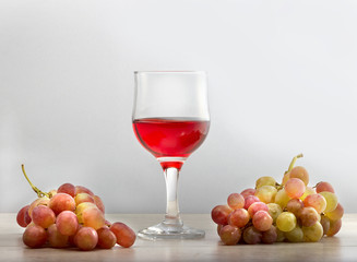Виноградное вино в стеклянном бокале и грозди винограда .\Полезное натуральное виноградное вино.