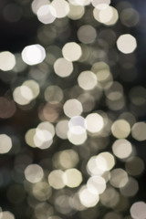 Christmas background has beautiful colored bokeh. Blurry texture of a lit garland for holiday. 