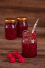 Raspberry jam in a jar on the wooden table