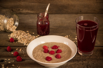 Oatmeal porridge with raspberries and compote on the wooden tabl