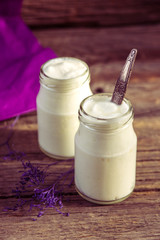Yogurt in jar on the wooden table with purple dried plant