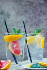 Two glass cups of water with red orange, lemon, mint and ice. Fr
