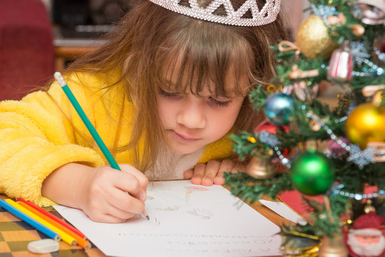 The girl draws a picture in a letter to Santa Claus