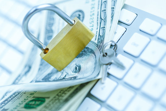 Security lock on dollar bills with white computer keyboard