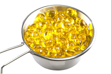 Stainless steel bowl with Norwegian salmon oil omega 3 gel capsules. Natural Supplement for vascular health. White background.