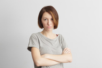 Fototapeta premium Girl with distrust and doubt looks forward, her arms crossed over her chest.