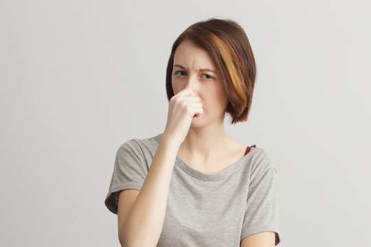 Girl closes her nose because of the odor and stench.