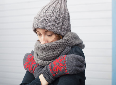 Beautiful girl in a knitted cap and mittens freezing in winter