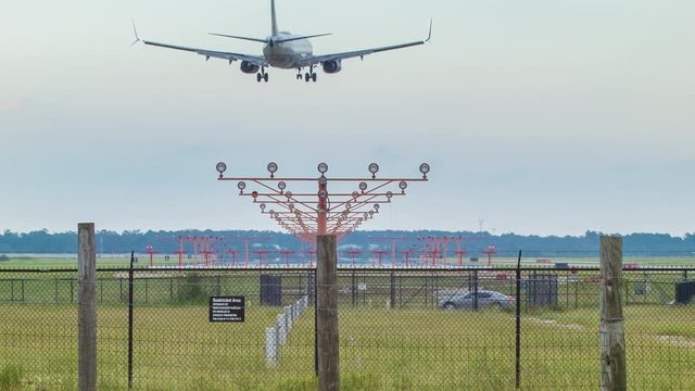 Jet Airliner Landing at Airport Over Approach Lights in Daytime Seen from Back with Smoke from Tires Wide