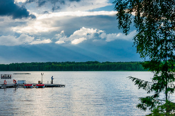Calm heavenly landscape with thick clouds over the forest lake, good place to fishing