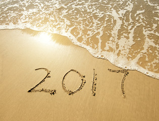 2017 written in sand write on tropical beach