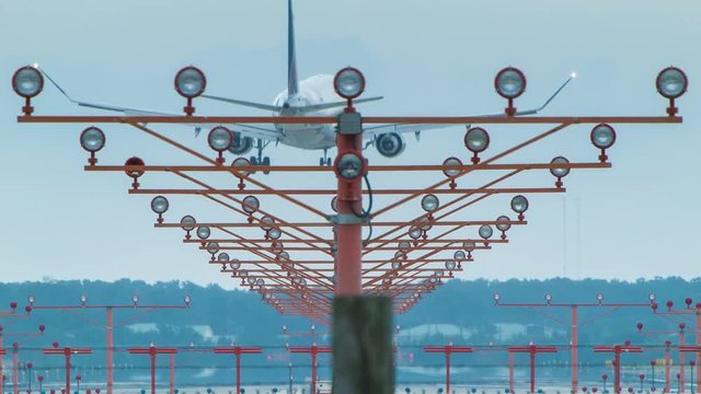 Jet Airliner Landing at Airport Over Approach Lights in Daytime Seen from Back with Smoke from Tires Close-up