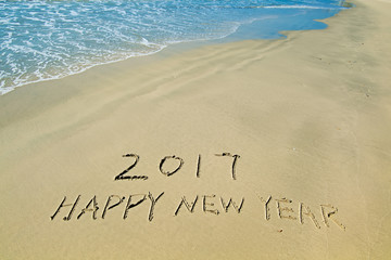 2017 happy new year written in sand write on tropical beach