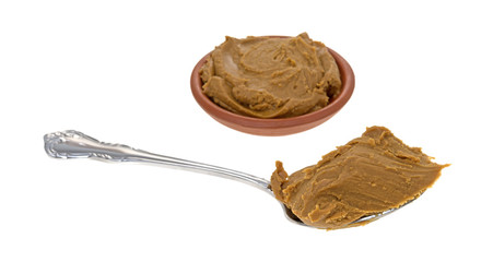 Cookie butter in a bowl and on a spoon isolated on a white background.