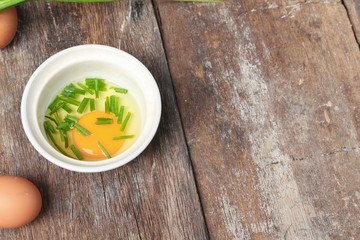 Raw egg in a bowl selective focus and onion on wooden table