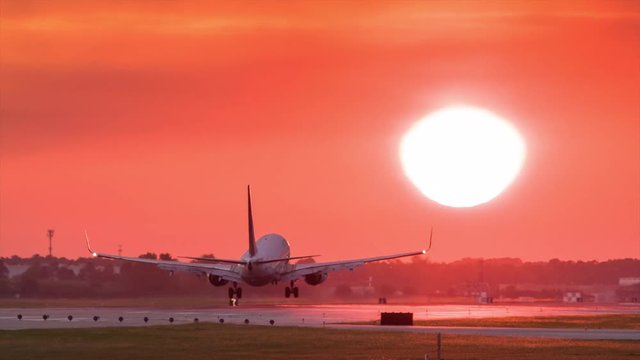 Commercial jet airliner landing on runway at sunset