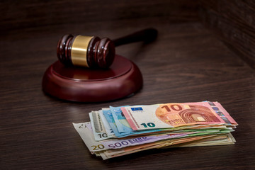 Wooden gavel on euro banknotes on wooden desk.