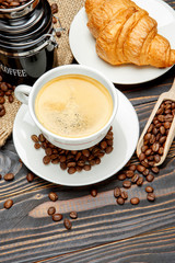 cup of coffe and croissant on wooden background