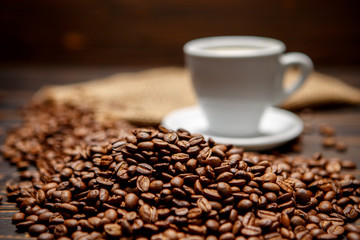 roasted coffee beans and cup on wooden background