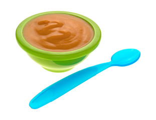 Baby food in a green bowl with a spoon to the side isolated on a white background.