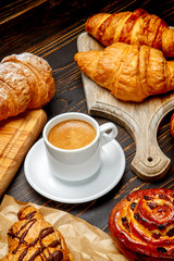cup of coffe and croissant on wooden background