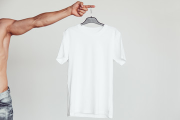 Guy with naked torso holding a white T-shirt in his hands. Branding Mock-Up.