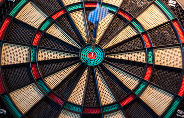 Blue dart in the center of a colorful dartboard target