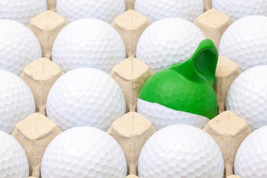 White golf balls in the box for eggs. Golf ball with funny cap.