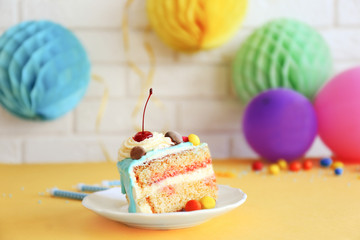 Saucer with piece of Birthday cake and decor on brick wall background