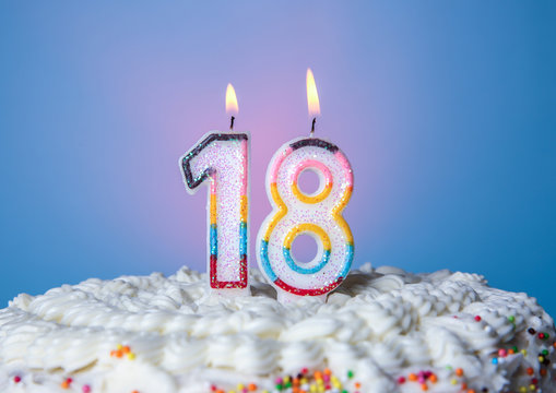 Tasty cake with candles for eighteenth birthday on blue background