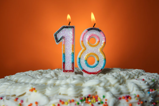 Tasty cake with candles for eighteenth birthday on orange background