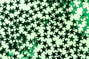 Bright confetti in shape of stars, on green background. Close up
