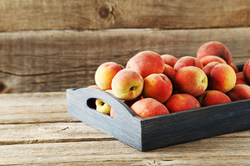 Sweet peach fruit in tray on grey wooden table