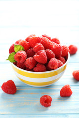 Red raspberries in bowl on a blue wooden table