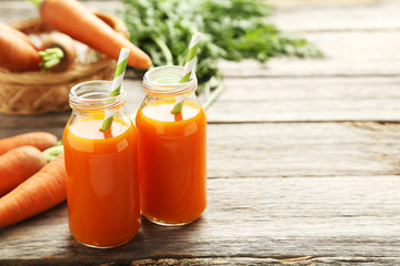 Fresh carrot juice in bottles on a grey wooden table