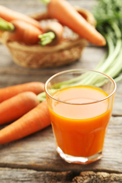 Fresh carrot juice in glass on a grey wooden table