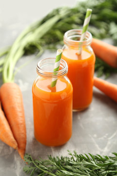 Fresh carrot juice in bottles on a grey background