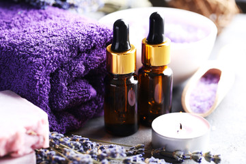 Lavender oil with soap and flowers on grey table