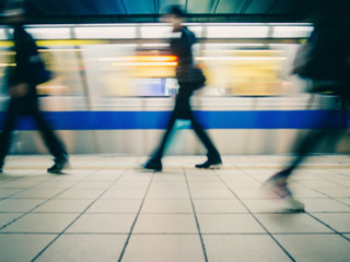 Subway train leaving station. People coming to or leaving the platform. Motion blur. City life. Slightly blue-toned.