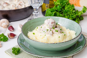 Meatballs in a creamy sauce with mushrooms and mashed potatoes in a plate
